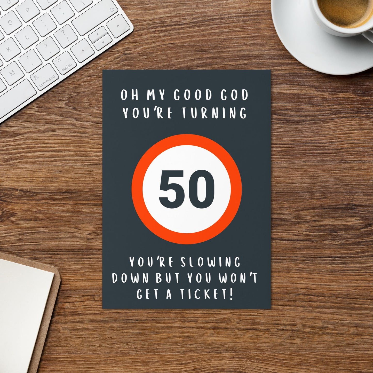 50th Birthday Card, grey background, red speed sign (50 mph / kmh) birthday card, on table with cup of coffee and keyboard